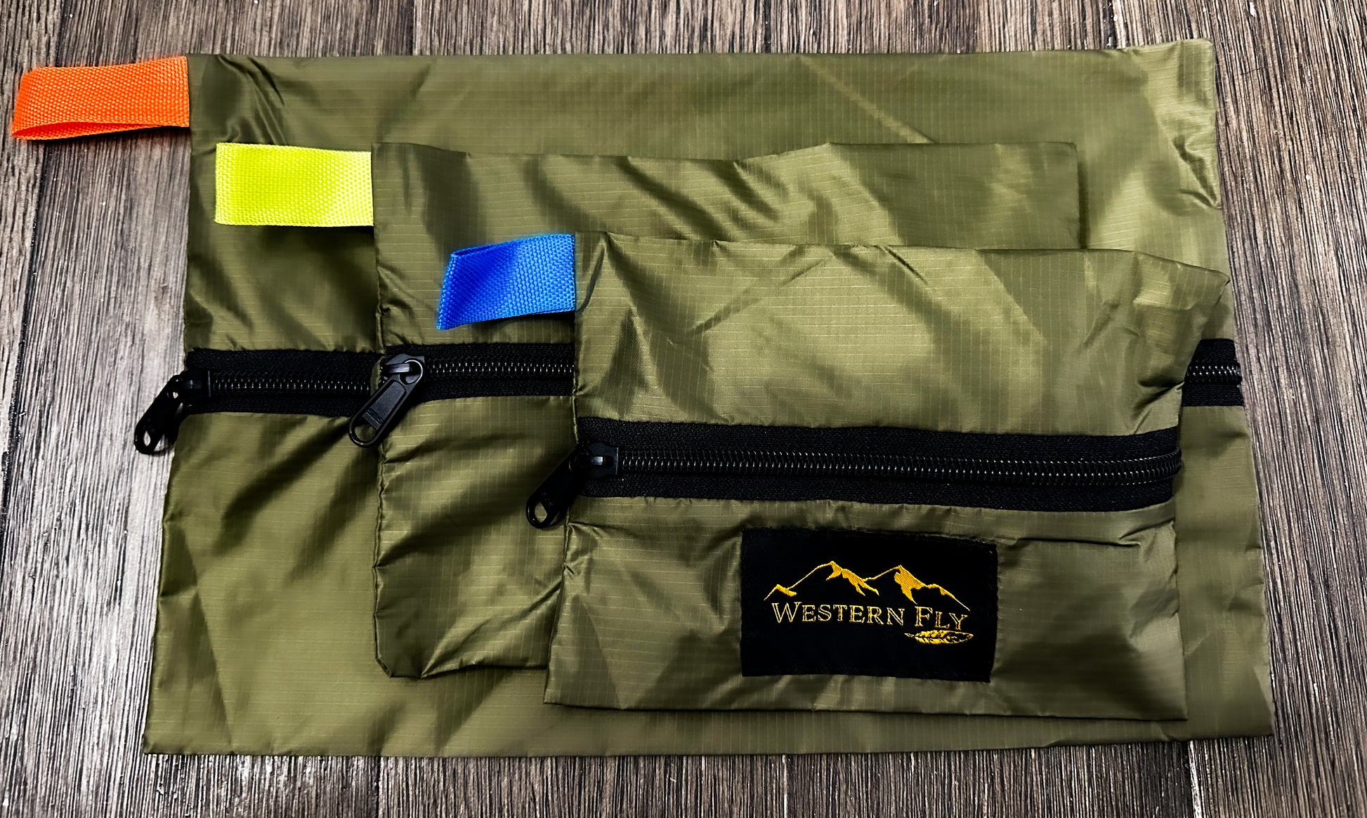 Green pack with colorful tags and Western Fly logo on a wooden surface