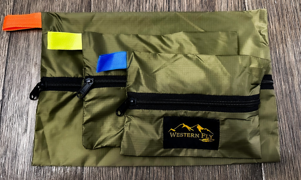 Green pack with colorful tags and Western Fly logo on a wooden surface