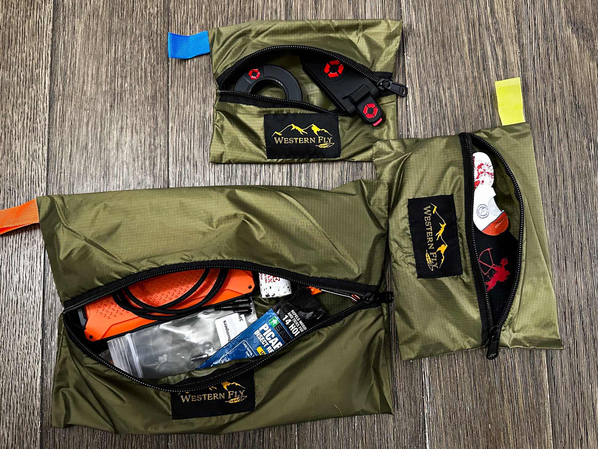 Green packs with contents on a wooden surface, featuring 'Western Fly' branding.