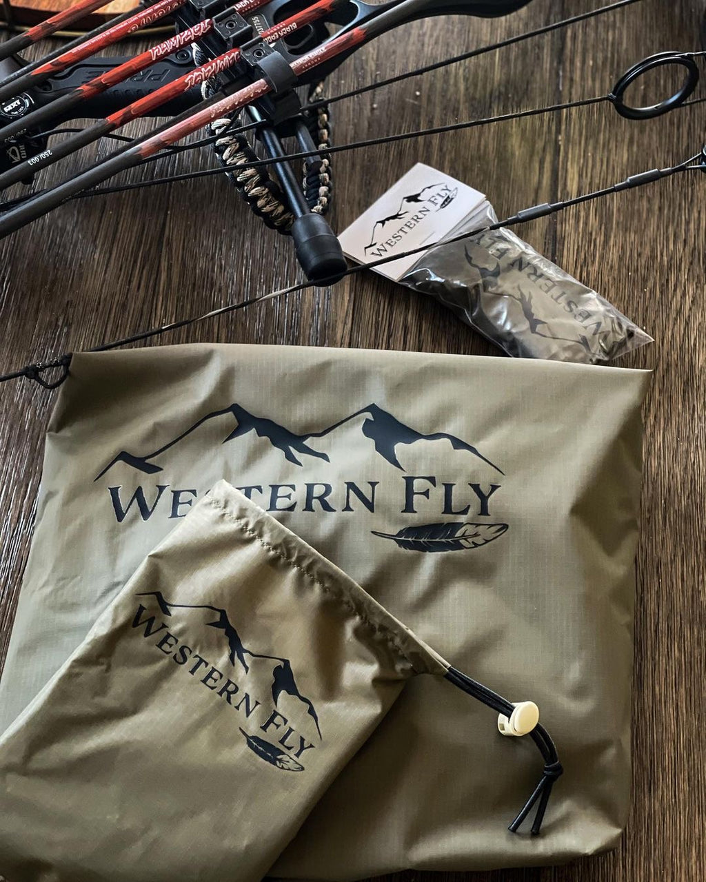 Archery set with bows and arrows on a wooden surface, featuring 'Western Fly' branding and Pack Fly
